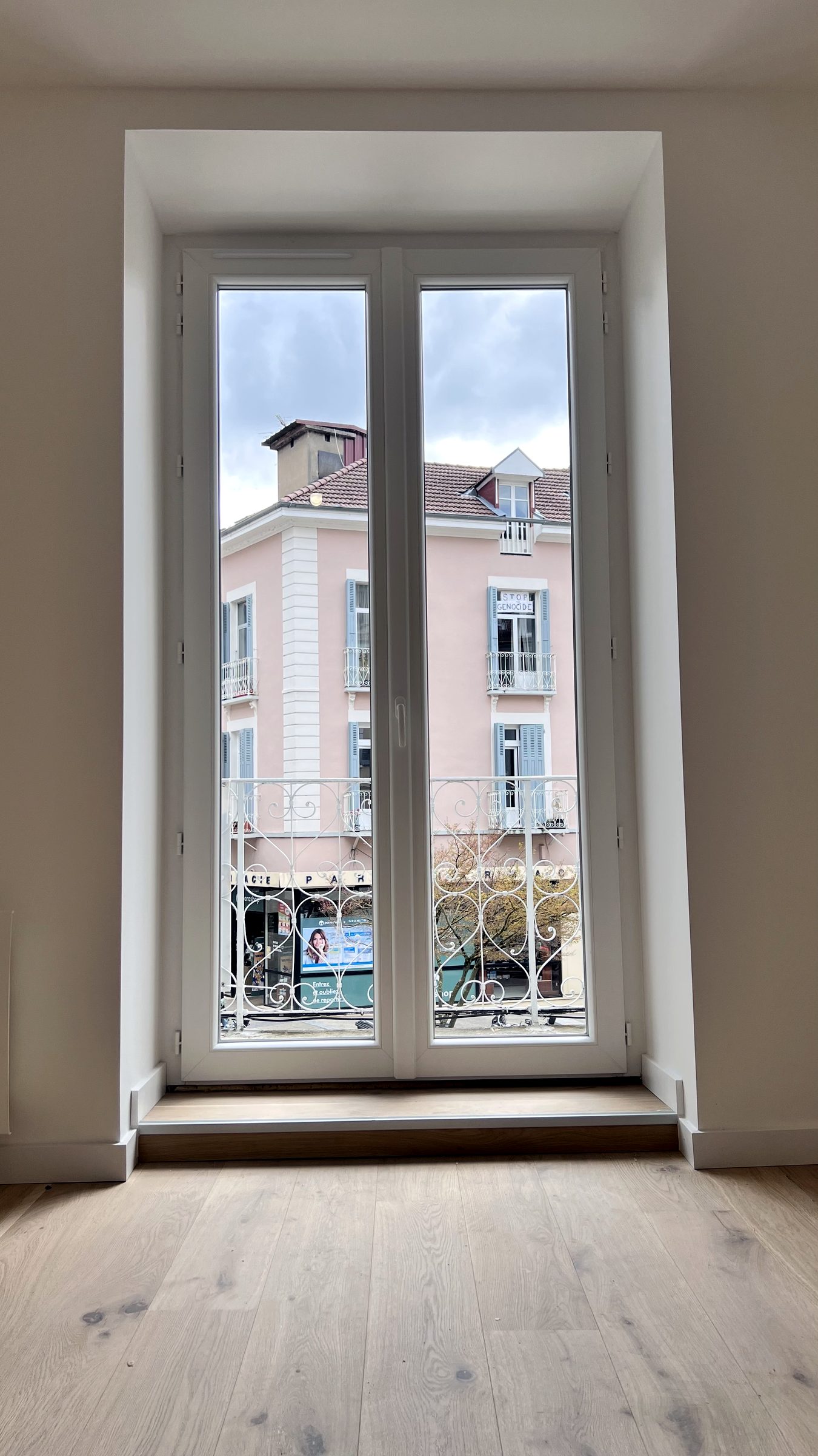 Porte-fenêtre ouverte sur les façades de Voiron